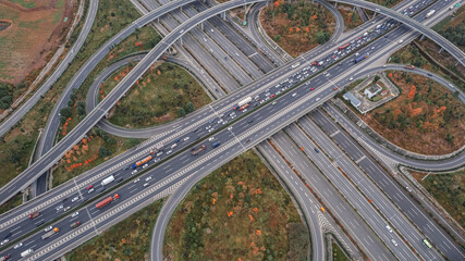 Top down aerial view from drone on modern traffic junction of multiple lane highway road in metropolis city. Heavy traffic on motorways. Elevated curved roads, clover shape bridge with no speed limit.