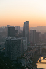 Fototapeta premium At sunset, the river banks flowing with vehicles, the sun's afterglow sprinkled on the skyscrapers, the river; in the distance is the sunset , the silhouette of the mountains, this is Chongqing, China