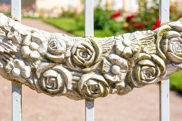 Decorative element of vintage forged white fence with garlands of flowers