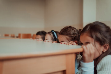 Funny child looking while hiding behind table. Back to school concetp. Selective focus