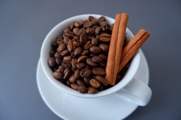 Obraz premium Coffee beans, Cinnamons and cup and saucer on gray background. Cafe, Coffee, restaurant design elements.