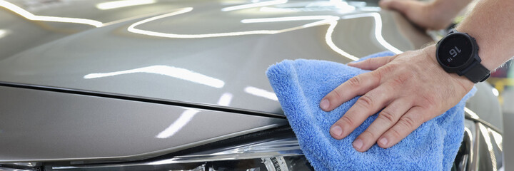 Man cleaning a car with microfiber cloth closeup