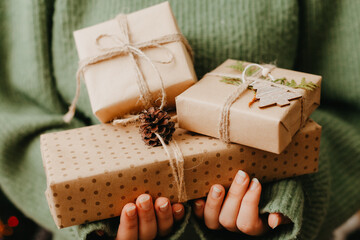 Female's hands in pullover holding many gift boxes.