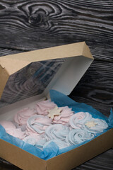 Marshmallow blue and pink. Lies in craft packaging. Decorated with mastic snowflakes. On black pine boards.