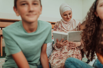 Female teacher helps school kids to finish they lesson.They sitting all together on floor.Selective focus