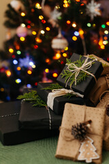 Some gift boxes laying on green textile, defocused light on Christmas tree on background