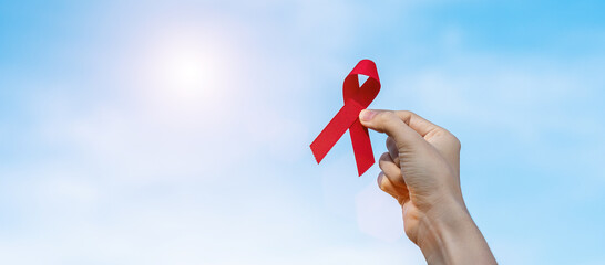 Hand holding Red Ribbon for supporting people living and illness. Healthcare and safe sex concept....