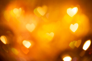 Natural yellow bokeh of lights in the form of a heart, blurred out of focus background. Abstract beautiful backdrop for text or advertising. Postcard with love in light gentle colors