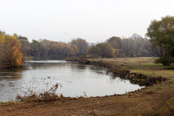 Landscape near to a river with trees and sky with dense clouds