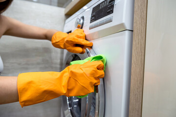 Woman in rubber gloves cleaning washing machine