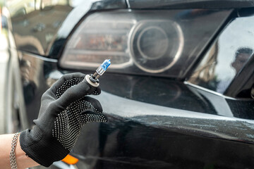 mechanic hand holding halogen light bulb near on car headlight