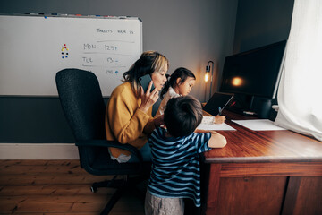 Working mother taking a phone call in her home office - obrazy, fototapety, plakaty