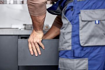 Handyman making kitchen wall cabinets in the apartment.