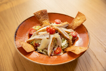 Caesar salad with chicken served on a wooden table