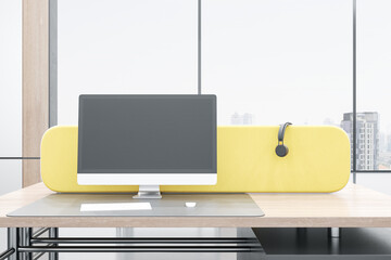 Close up of empty mock up computer monitor in modern bright coworking office interior with yellow partition, panoramic windows with city view, wooden furniture. 3D Rendering.