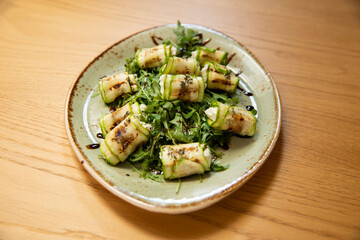 Grilled zucchini rolls with herbs, rocket, arugula and cheese