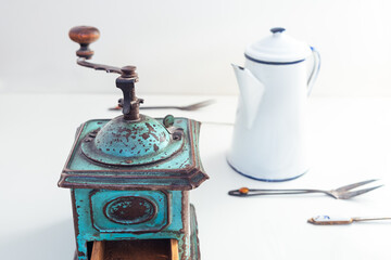 Beautiful, turquoise, antique coffee grinder with a white jug and old cutlery