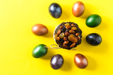 Easter cake with nuts and dried fruits on a yellow background with multi-colored colored eggs. the concept of the Easter holiday. top view.