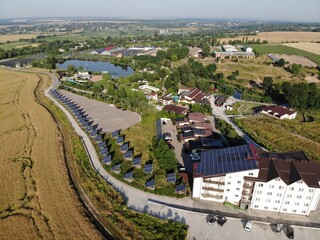 Solar panel on a red roof reflecting the sun and the cloudless blue sky