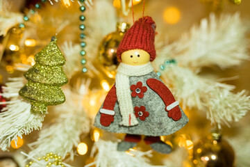 Close up of holidays location with doll toy and garlands on white yellow Christmas tree