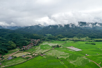 Scenic view of  green field against mountain in cloudy sky