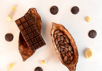 Cocoa cacao pod with beans, chocolate bar and cocoa butter on white background. Confectionery ingredients. Top view.
