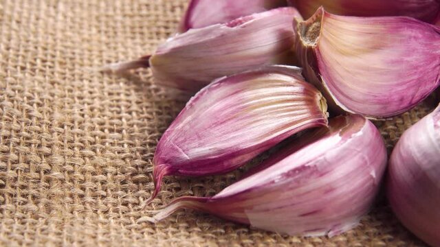 Red garlic cloves on a rustic rough burlap. Macro. Rotation