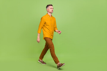 Full size profile side photo of mature man go look empty space wear casul clothes isolated over green color background