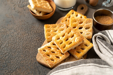Puff cookies on a serving wooden board on a dark culinary background. Delicious homemade sweet pastries close-up