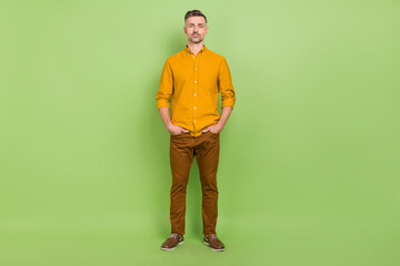 Full body photo of good white hairdo mature man stand wear yellow shirt pants isolated on green color background