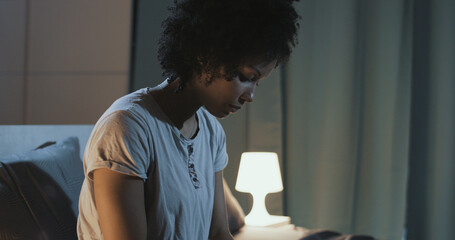 Sad woman sitting on bed at night