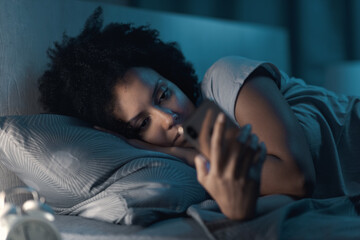 Sleepless woman connecting with her smartphone at night
