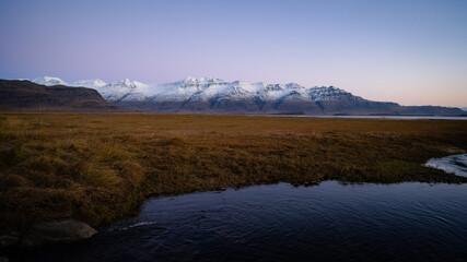 View during sunrise near ring road at Iceland with snowy mountains in the background