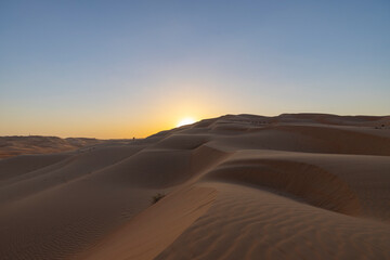 Obraz na płótnie Canvas Sunset in the arabian desert with rolling sand dunes in Abu Dhabi, United Arab Emirates