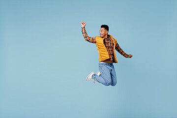 Full size body length jubilant exultant young black man 20s years old wears yellow waistcoat shirt looking aside jump raise hand arm up isolated on plain pastel light blue background studio portrait.