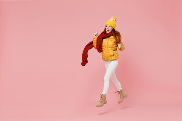 Full size body length excited young woman 20s wears yellow jacket hat mittens look aside keeping...