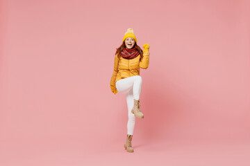 Full size body length cheerful fun young woman 20s wear yellow jacket hat mittens doing winner...