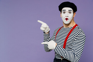 Surprised ecstatic young mime man with white face mask wears striped shirt beret pointing aside on...