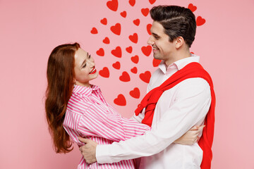 Young happy lovely couple two friends woman man 20s wearing casual shirt look to each other hug cuddle isolated on plain pastel pink background studio. Valentine's Day birthday holiday party concept.