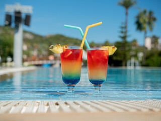 Relax by the pool. Summer vibrant cocktails with a straw sit by the pool.