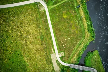 Foto auf Acrylglas Drone uitzicht op de rivier de Vecht, groen gras, blauw water, stad met hoogspanningspalen. Een fietser op het fietspad bij de brug. Vechtdal, Dalfsen Nederland © Dasya - Dasya