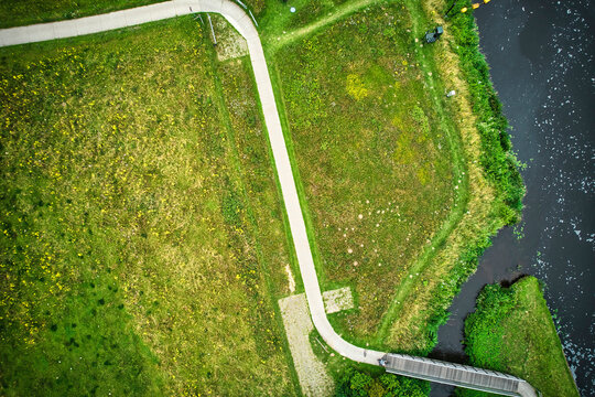Drone uitzicht op de rivier de Vecht, groen gras, blauw water, stad met hoogspanningspalen. Een fietser op het fietspad bij de brug. Vechtdal, Dalfsen Nederland