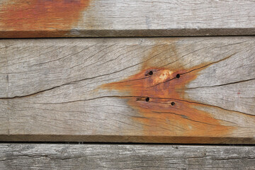 A close-up of old wooden beams covered with rust stains
