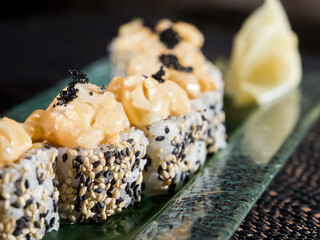 uramaki sushi roll with chopped scallop and sesame on dark background