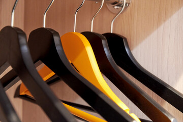 Many wooden hangers in the locker with one different orange hanger. Clothes storage backgrounds. Conceptual images