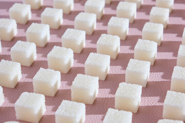 Refined sugar on pink background.Cubes of sweet and white sugar in geometricshape. Hard shadows.