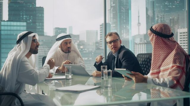 International Business Consultant Advices on Diversification of Investment Portfolio to Successful Arab Company Owners. Multicultural Meeting in Modern Office Between American and Emirati Businessman