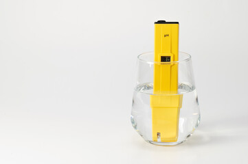 pH meter in a glass of water on a white background. Measuring the characteristics of drinking water. Hardness of water. Drinking water quality analyzer showing the level of dissolved solids