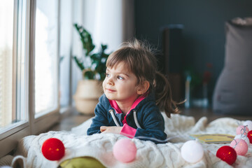 Little girl looking through the window at home