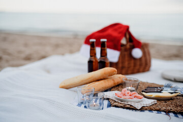Beach picnic with shripms, beer, candles and santa hat. Exotic new year and Christmas